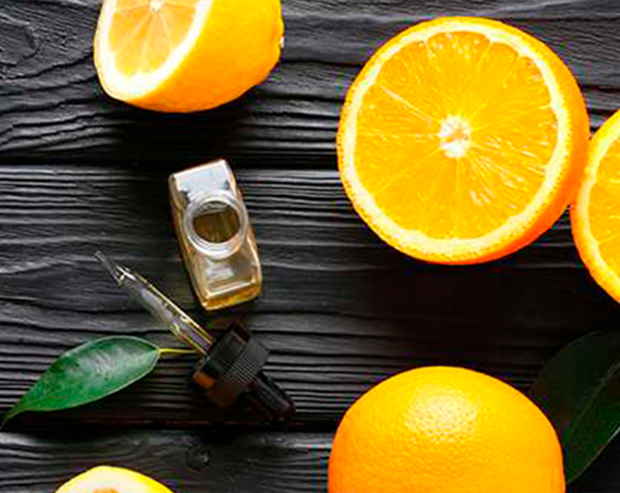 Frische Zitrusfrüchte und Essenz-Fläschchen mit Pipette auf einem Holzuntergrund.